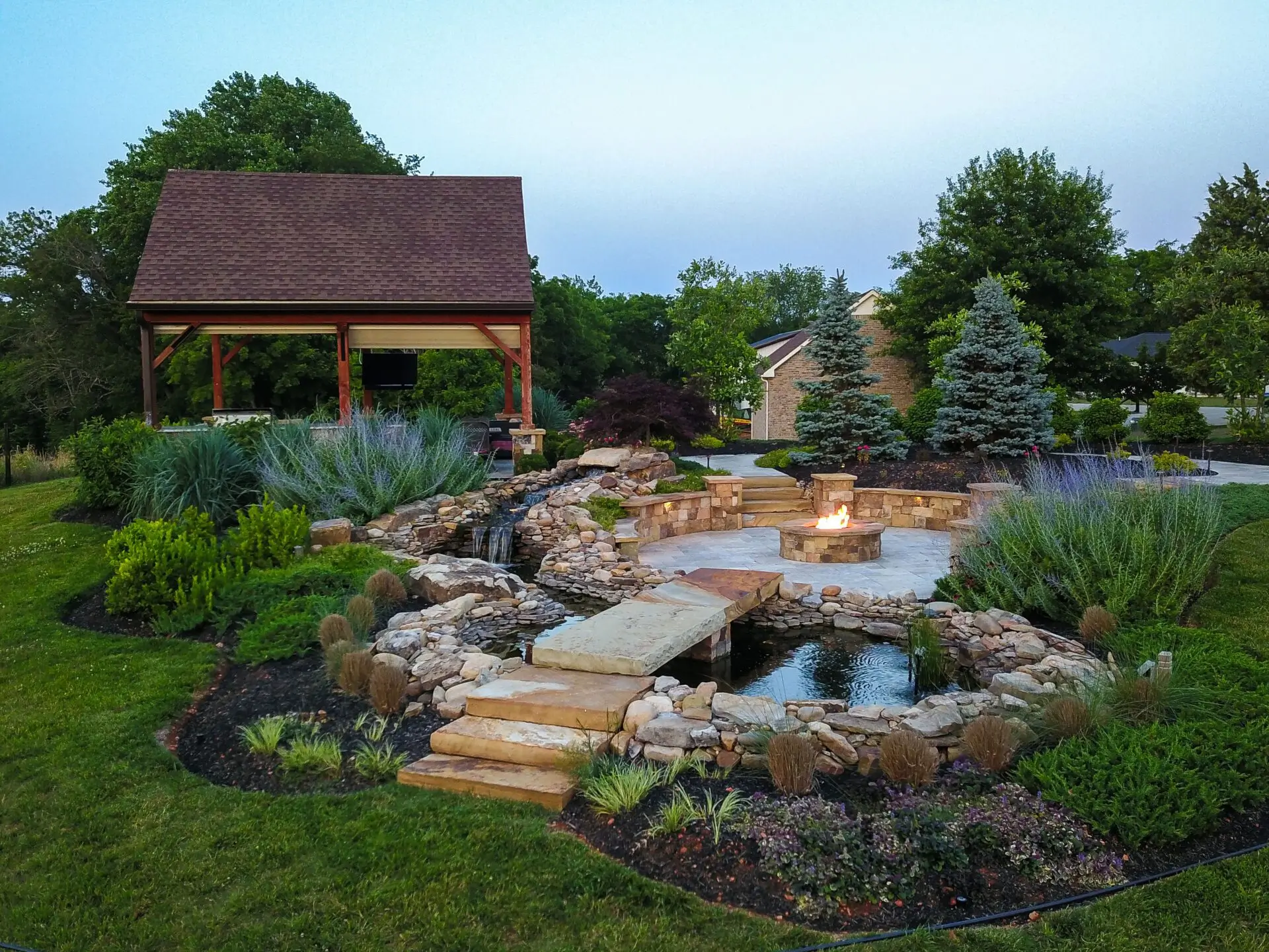 A serene backyard featuring a cozy fire pit surrounded by seating and a tranquil water feature nearby.