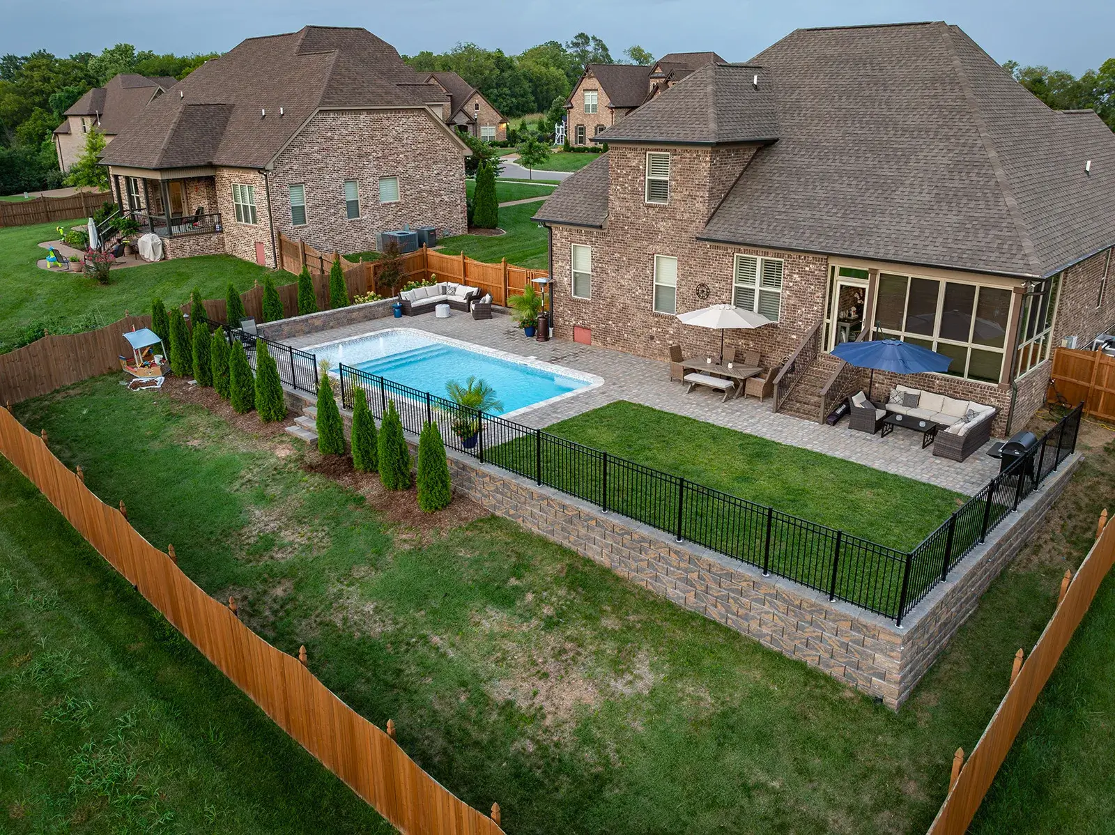 A backyard featuring a swimming pool surrounded by a fence, showcasing a serene outdoor space for relaxation.