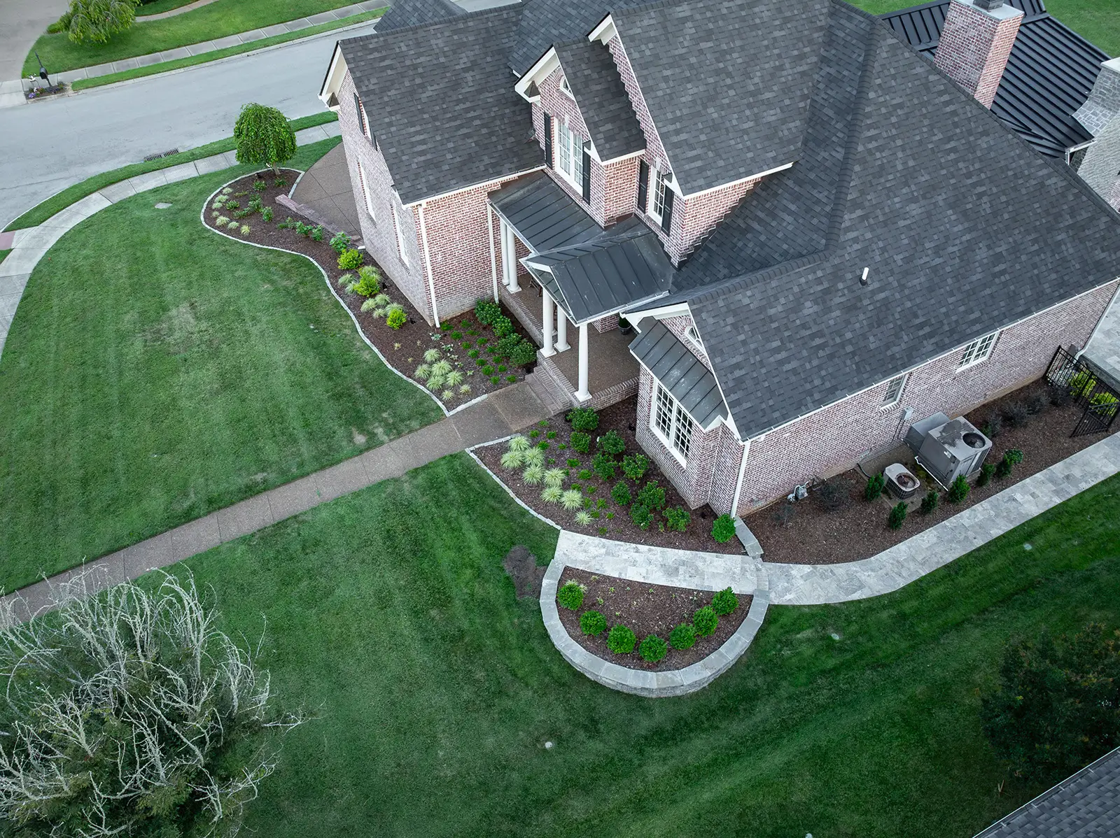  Aerial view of a spacious home featuring a driveway and well-maintained landscaping surrounding the property.
