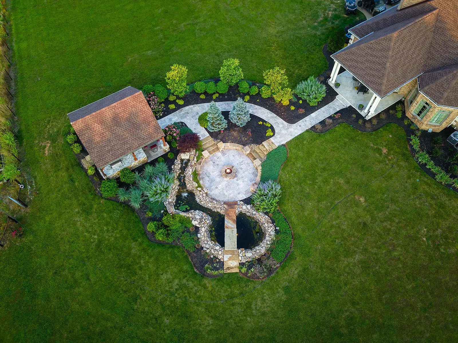 Aerial view of a home featuring a fountain and a lush garden, showcasing the landscape and architectural design.
