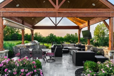 A covered patio featuring a grill and vibrant flowers, creating a cozy outdoor dining space.