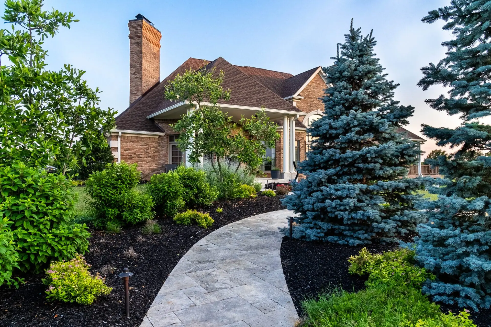 A picturesque house featuring a pathway that guides visitors to the welcoming front door, framed by vibrant landscaping.
