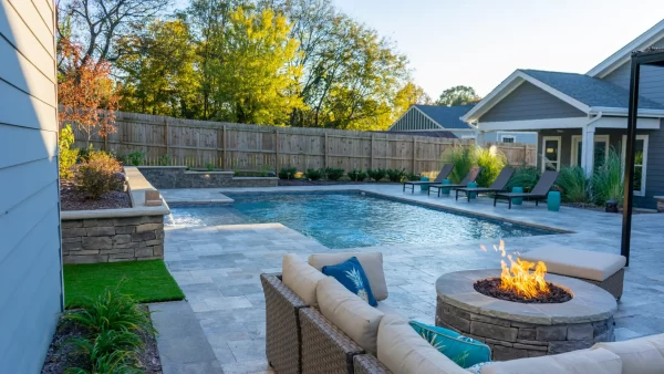 A backyard scene with a grill, a refreshing pool, and a fire pit for gatherings.