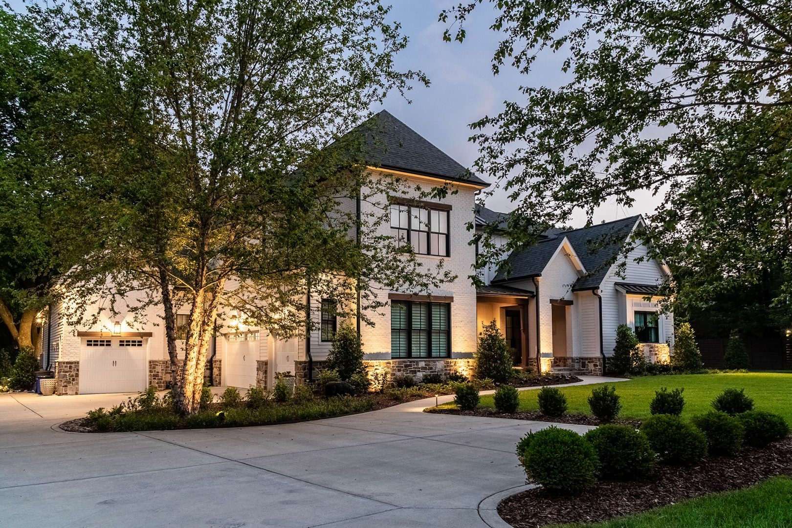 A lovely residence with a driveway and greenery from surrounding trees, highlighting a peaceful and attractive setting.